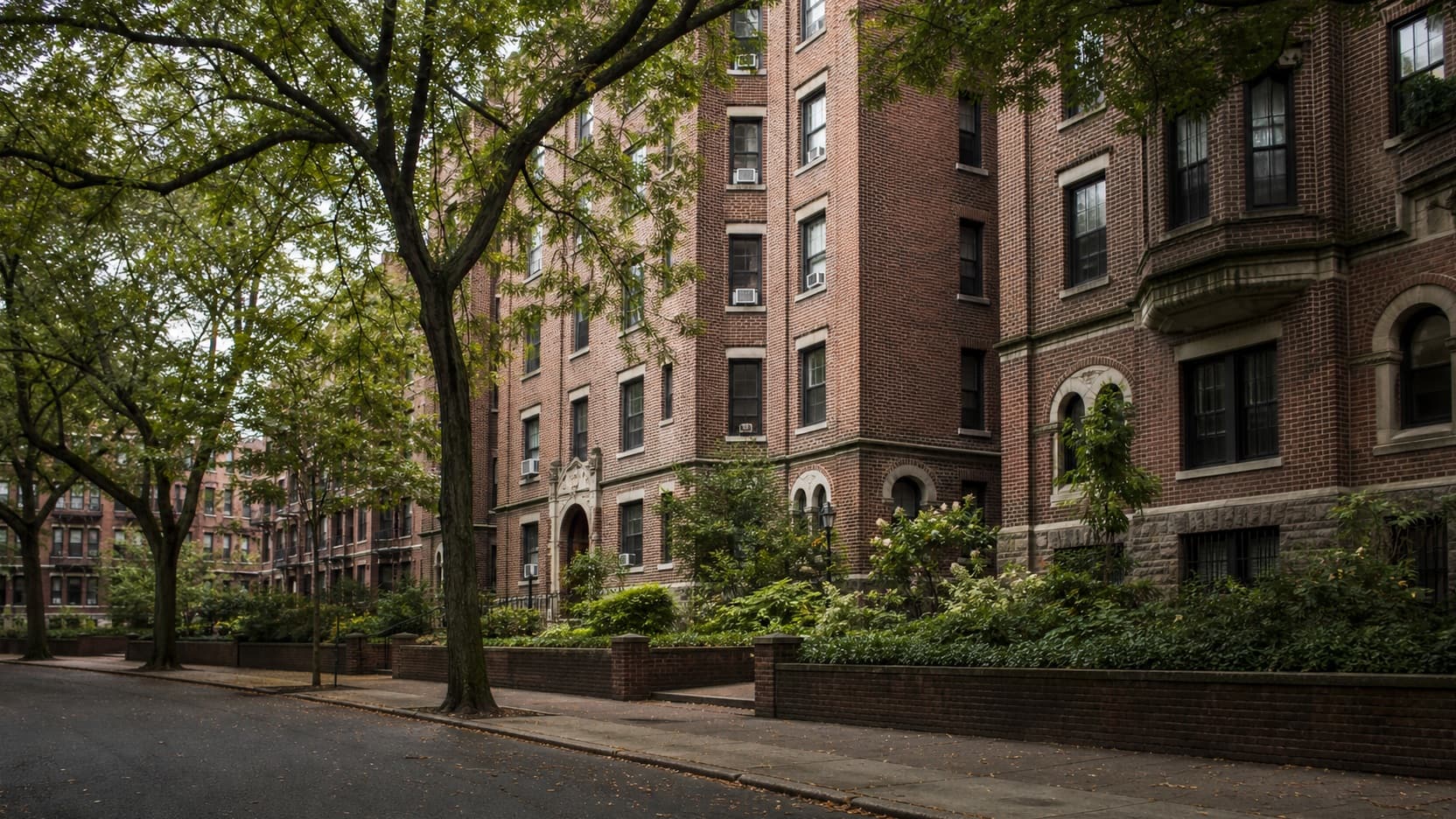 A street of pre-war brick garden apartment buildings with arched entryways