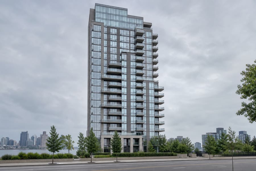 A recent glass and grey panel residential tower with stepped balconies