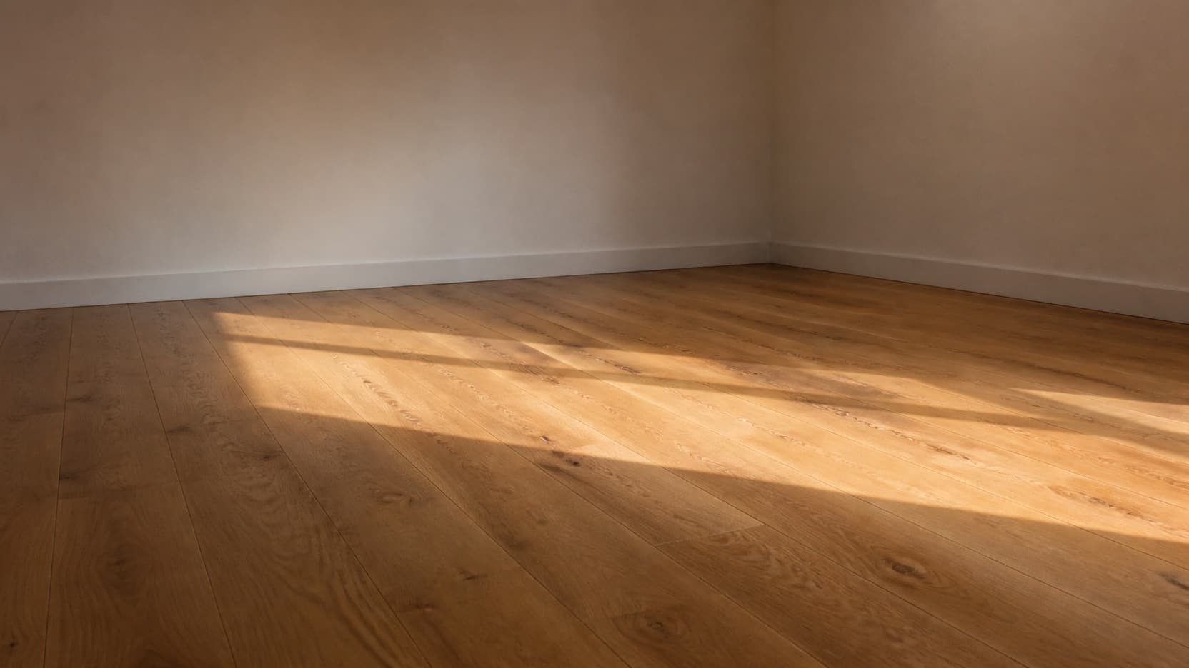 A quiet empty room with a finished oak floor and afternoon light falling across it